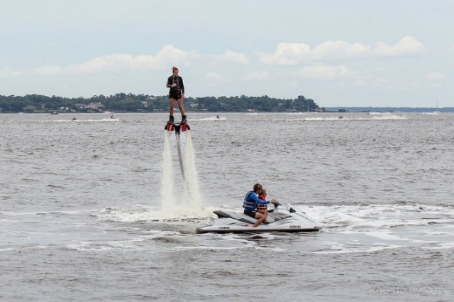 chica practicando flyboard mientras dos personas conducen una moto de agua